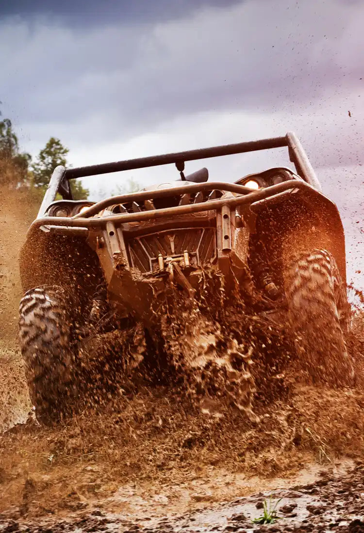 Mud-splattered off-road vehicle with roll cage and aggressive tires